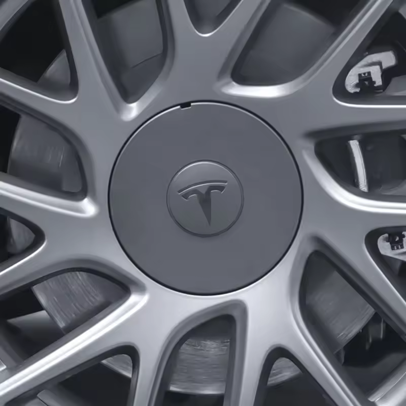 Lähikuva Keskikupit Model 3 Highlandin Photon-vanteisiin: hopeinen kevytmetallivanne Tesla-logolla, jossa on geometrinen pyöränkehä ja näkyvä jarrulevy, joka korostaa Tesla-lisävarusteiden ensiluokkaista laatua.